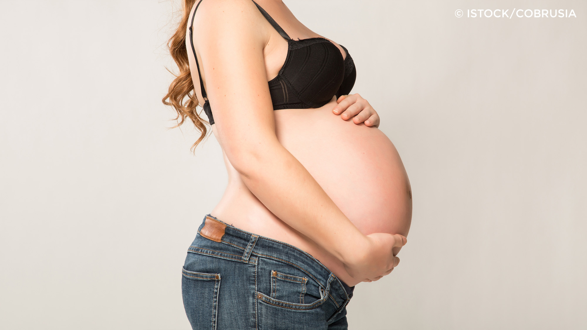 Schwangere Frau mit den Händen auf dem Bauch